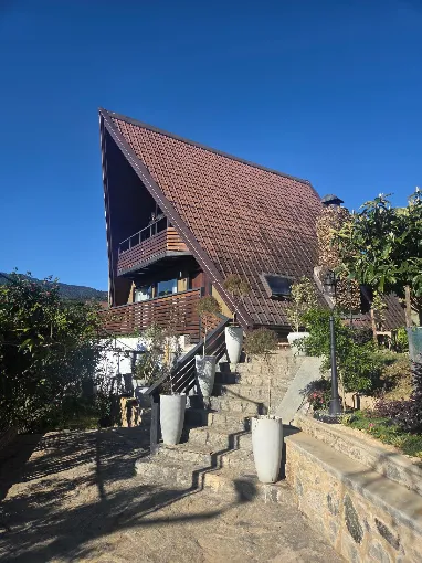 Kubana chalet under a clear blue sky with stone steps