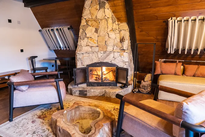 Lit stone fireplace with armchairs and a carved wooden table