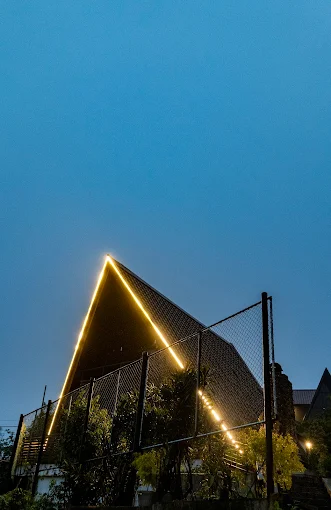 The A-frame roofline outlined in warm light at night