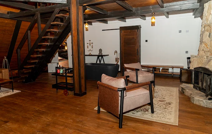 Sitting area with exposed beams, staircase and armchairs