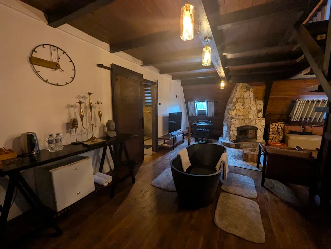 Living room with a freestanding black bathtub facing the stone fireplace
